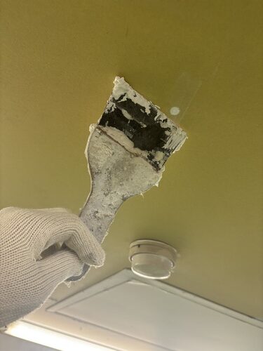 掛川市の工場天井で浮いた旧塗膜を除去する様子