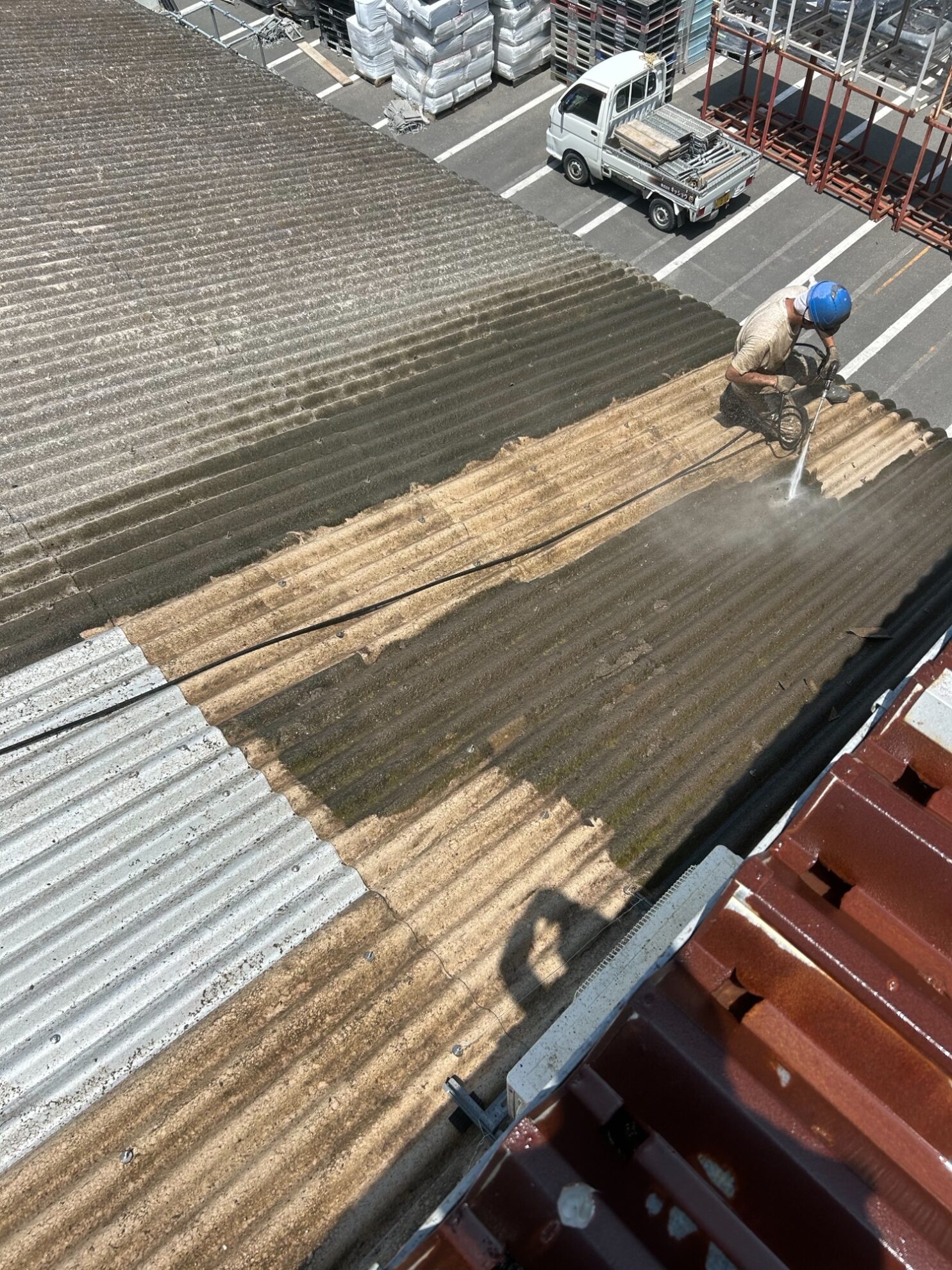 掛川市工場のスレート屋根を高圧洗浄して、長年の汚れやコケを落としている施工写真