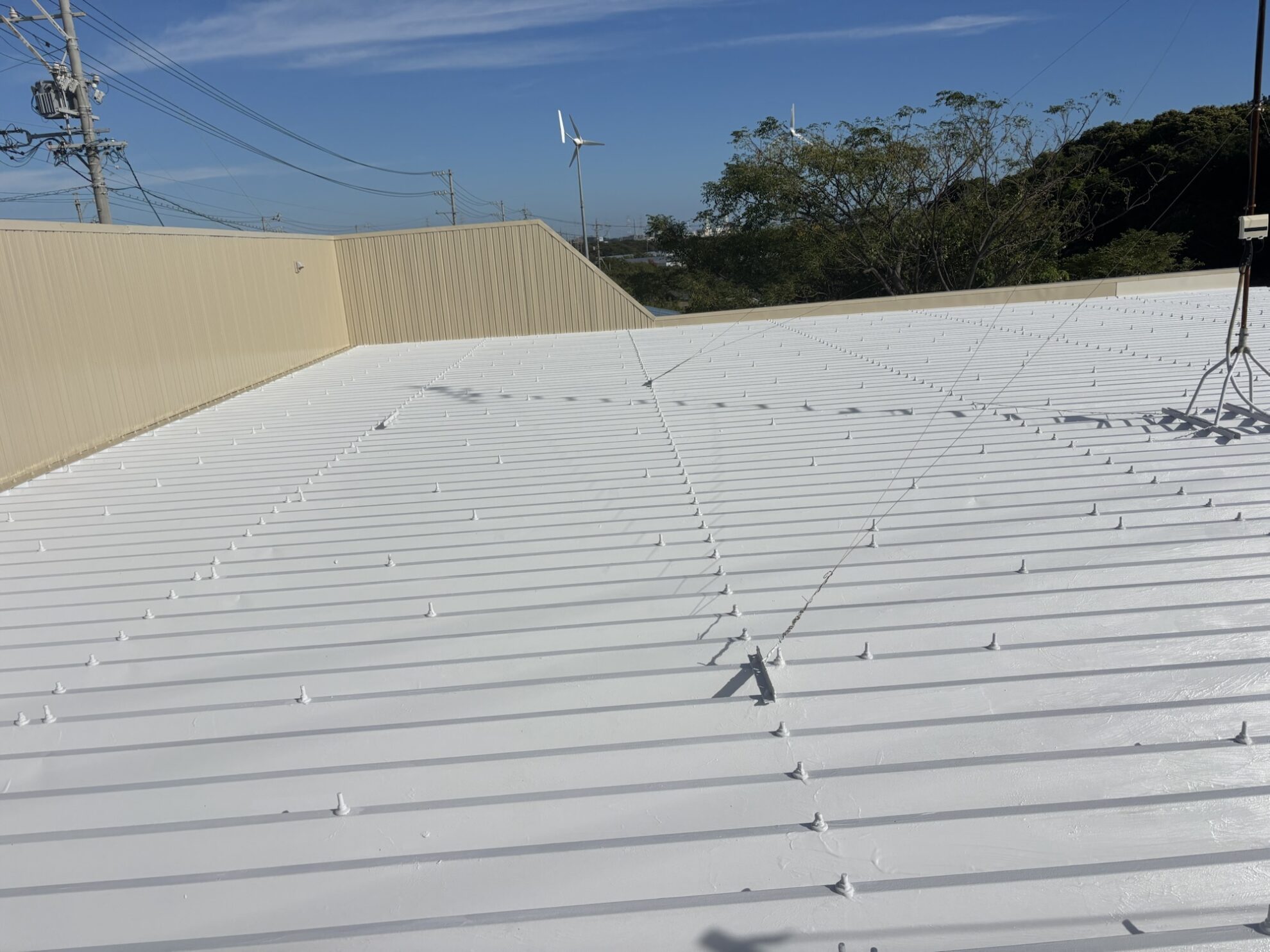 遮熱塗料キルコートで上塗り中の折半屋根。職人が丁寧に仕上げている掛川市の店舗施工現場